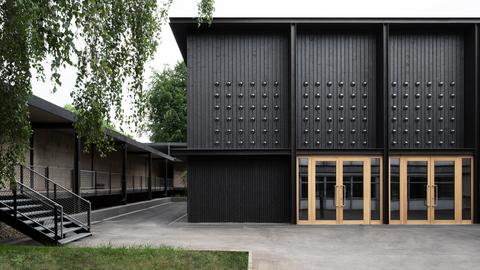 Gebäude mit schwarzer Holz-Fassade und hellen Türen