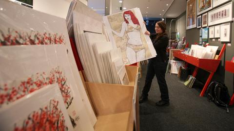Eine Frau stellt am Mittwoch (18.11.2009) im Gebäude des Kunstsupermarktes in Frankfurt am Main ein Bild in ein Regal. 