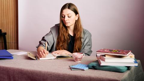 Das Bild zeigt Kabarettistin Lara Ermer an einem Schreibtisch sitzend.