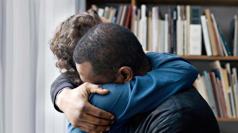 Ein schwarzer Mann und eine weiße Frau umarmen sich.