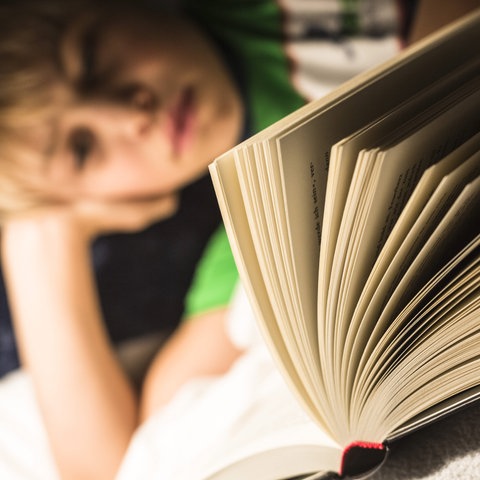 Ein Kind blättert im Liegen in einem Buch
