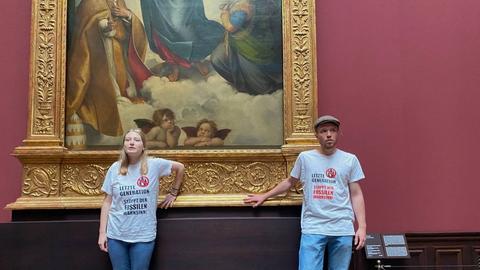 Zwei Aktivisten kleben am goldenen Rahmen des Raffael-Gemäldes Sixtinische Madonna in Dresden