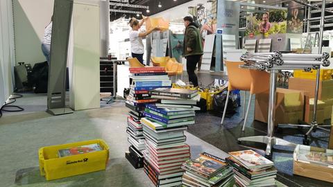 Herumliegende Bücher, Kartons und Menschen, die abbauen und einpacken