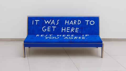 Eine blaue Bank mit der Aufschrift "It was hard to get here. Rest here if you agree."
