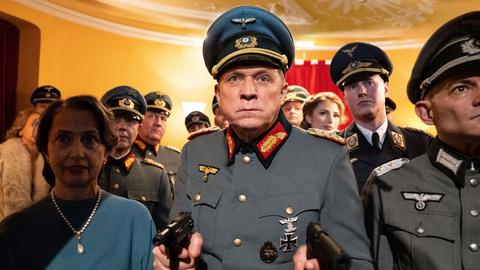 Komissar Murot steht in einer Nazi-Uniform in einer Menschenmengen und schaut direkt in die Kamera. 