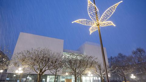 Modernes Gebäude in winterlicher Dämmerung, im Vordergrund eine blütenförmige Straßenlampe