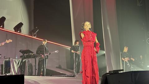 Nina Chuba performt im roten Ganzkörperdress auf der Bühne, eingehüllt in rotes Licht.