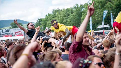 Menschenmenge bei einem Konzert. Zwei Menschen "surfen" auf der Masse von Menschen.