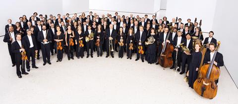 Das hr-Sinfonieorchester steht im Halbrund und posiert für die Kamera.