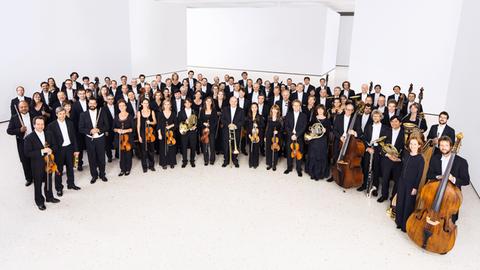 Das hr-Sinfonieorchester steht im Halbrund und posiert für die Kamera.