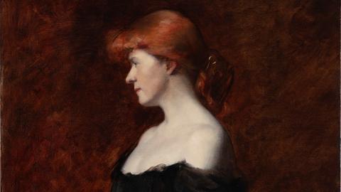 Das Bild von Ottilie W. Roederstein zeigt eine Frau mit roten Haaren und einem schwarzen, schulterfreien Kleid. Sie schaut schüchtern über ihre Schulter von der Kamera weg und hält einen Blumenstrauß in den Händen.