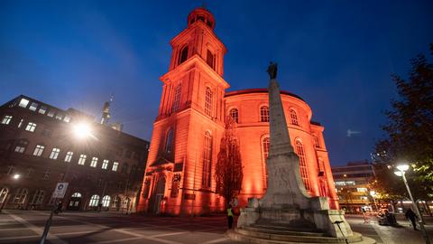 Die Paulskirche in Frankfurt wird mit orangefarbenem Licht angestrahlt.
