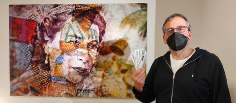 Pete Jones neben einem seiner Werke  - Queen in Geldscheinoptik. Jones hält Geldscheine in der Hand.