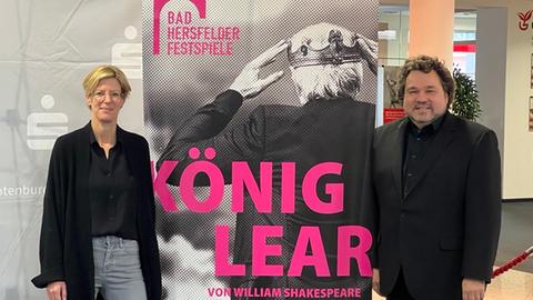 Frau und Mann vor einem Plakat Bad Hersfelder Festspiele 2023