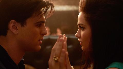 Filmszene aus "Priscilla". Zu sehen sind Jacob Elordi als Elvis Presley und Cailee Spaeny als Priscilla. Sie schauen sich in die Augen und heben jeweils eine Handfläche, um sie flach aneinander zu pressen.