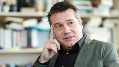 Philosoph Rainer Forst: Mann sitzt auf Stuhl und stützt seinen Kopf mit einer Hand ab