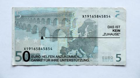 Von Künstler Ralf Kopp veränderter Geldschein - unter der Brücke sitzt ein Mensch. Schriftzug: Das ist kein Zuhause.
