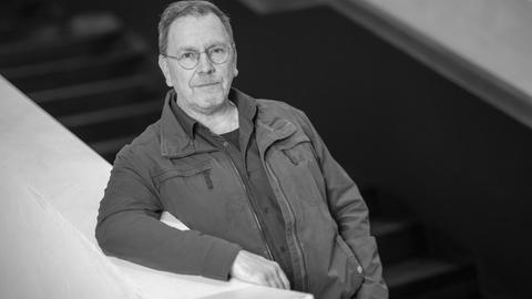 Der Theaterregisseur René Pollesch lehnt an einem Treppengeländer