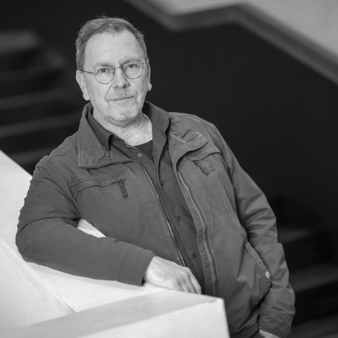Der Theaterregisseur René Pollesch lehnt an einem Treppengeländer