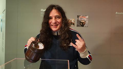 Tankard-Sänger Gerre hält einen Bierkrug mit dem nach der Band benannten Schlagenstern darin in der Hand.