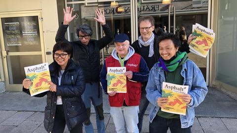 Fünf Menschen halten die Obdachlosenzeitung nach oben