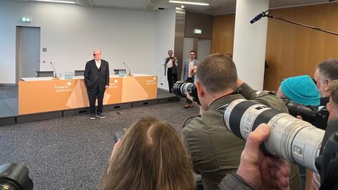 Salman Rushdie auf der Pressekonferenz in Frankfurt. Die Fotografen müssen fünf Meter Abstand halten. Das Bild zeigt die Fotografen von hinten, wie sie Ihre Objektive auf Rushdie richten.