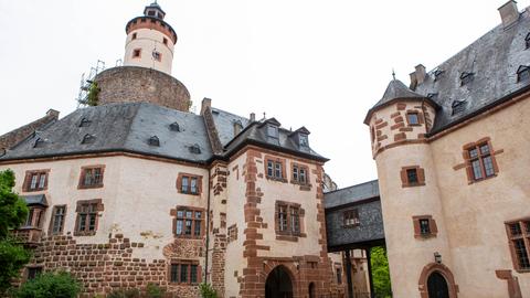 Das Bild zeigt das Büdinger Schloss, eine ehemalige Wasserburg aus hellem Sandstein und mit einem Turm.