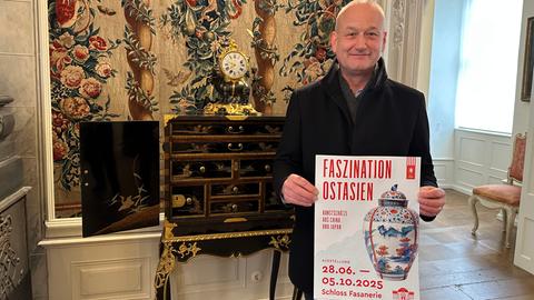 Der Museumsdirektor von Schloss Fasanerie, Markus Miller, präsentiert ein Plakat zu einer neuen Ausstellung. 