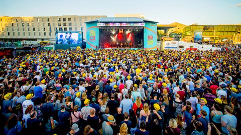 Blick auf eine Bühne beim Schlossgrabenfest. Eine Masse von Menschen steht vor der Bühne.