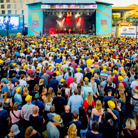 Blick auf eine Bühne beim Schlossgrabenfest. Eine Masse von Menschen steht vor der Bühne.