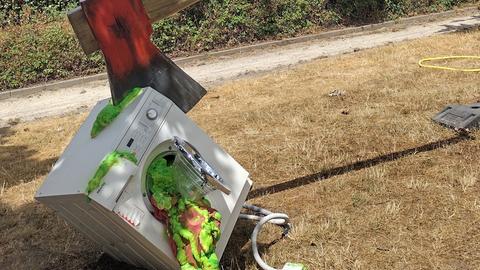 Skulptur einer Axt, die in einer Waschmaschine steckt