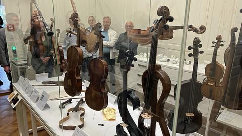 Menschen stehen an einer Vitrine mit alten Geigen