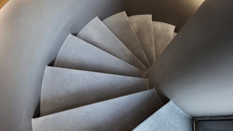 Eine enge, gewundene Treppe mit grauen Stufen