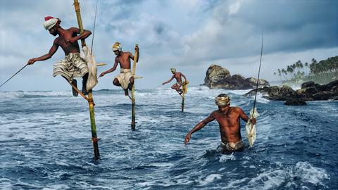 Fischer mit Turbanen sitzen auf Stangen im Meer