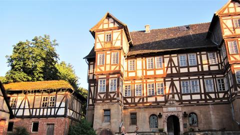 Altes Fachwerk-Gutshaus mit Mann, der einen Schimmel mit Kind auf dem Rücken führt