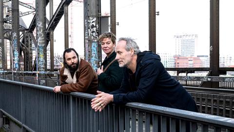Szene aus Tatort "Luna frisst oder stirbt": Eine Frau und zwei Männer stehen auf einer Brücke und unterhalten sich.