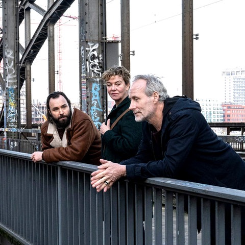 Szene aus Tatort "Luna frisst oder stirbt": Eine Frau und zwei Männer stehen auf einer Brücke und unterhalten sich.