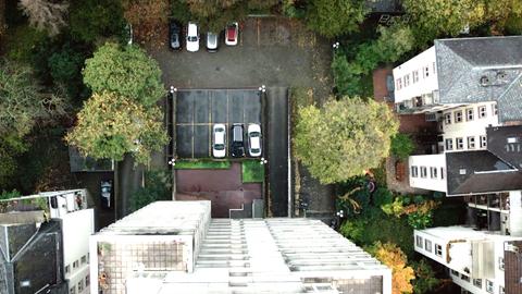 Der Blick von einem Hochhaus auf den Parkplatz, auf dem einige Autos stehen.