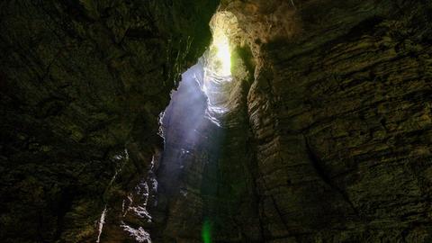Der Blick aus einer Höhle auf ein Loch, durch das Sonnenlicht einfällt
