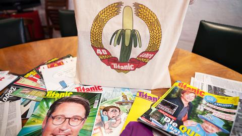  Eine Jubiläums-Stofftasche und einige Ausgaben des Satiremagazins Titanic liegen auf dem Konferenztisch in den Redaktionsräumen.