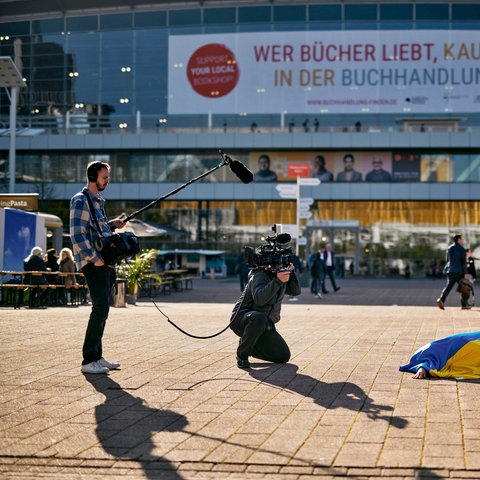 Performance der ukrainischen Künstlerin Maria Kulikovska - eingewickelt in eine Ukraine-Flagge liegt sie auf der Freifläche vor der Halle 3 der Frankfurter Buchmesse