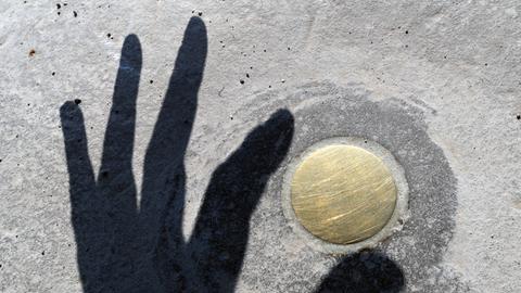 Der Schatten einer Hand greift auf dem Kasseler Friedrichsplatz nach dem "Vertikalen Erdkilometer" des US-amerikanischen Künstlers Walter de Maria