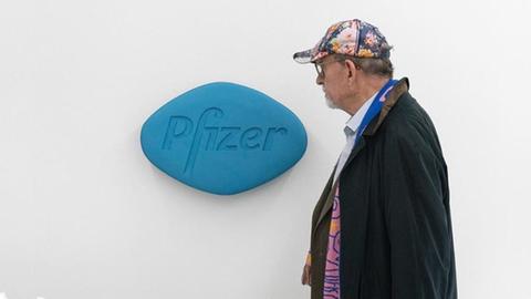 Ein Mann geht an einer übergroßen Viagra-Pille vorbei, die an der Wand hängt.