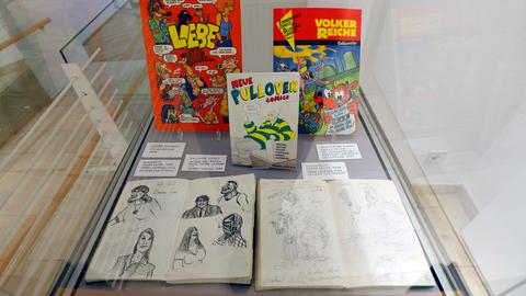 Das Bild zeigt eine Glasvitrine, in der verschiedene Comic-Hefte ausgestellt sind.