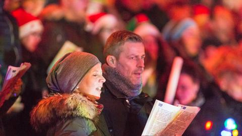 eine Frau und ein Mann singen in einer Menschenmenge