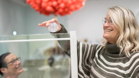 Eine Frau wirft eine gläserne Kugel in einen Brunnen