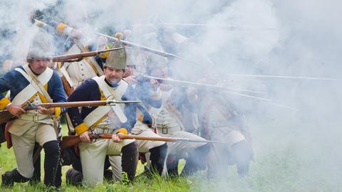 Historiendarsteller, kostümiert als Soldaten des hochfürstlich hessen-casselischen Füsilier-Regiments von Ditfurth, schießen auf Schloss Fasanerie während des Historienfestivals "Zeitreise ins 18. Jahrhundert".