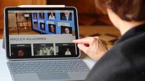 Eine Frau tippt auf einen Bildschirm, auf dem Zeitzeugen-Interviews im Internet abrufbar sind. 