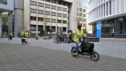 Sicherheitstrainings-Teilnehmende in Warnwesten fahren Lastenräder auf dem Campus