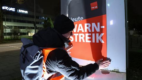 Streikender hängt Plakate mit der Aufschrift "Heute Warnstreik" bei der Lufthansa Technik auf. 